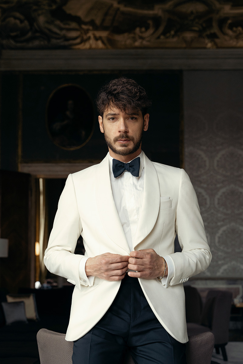 Andrea wears a white tuxedo and a luxury bow tie in Scabal Diamanti fabric in the Aman Venice location in Venice
